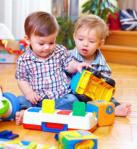 Two toddlers playing with toys - Hand, foot and mouth awareness