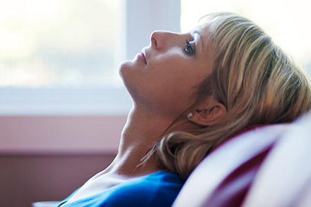 Woman sitting on couch with her head leaning back - Depression in adults