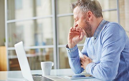 Man yawning at work - Reasons you are always tired