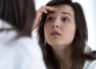 Teenage girl examining her face in the mirror - Teen acne