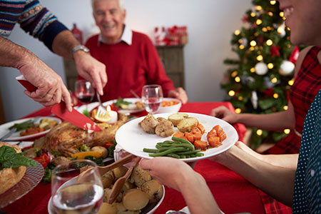 Person holding their plate up to be served turkey at a holiday dinner - Holidays: Eating with moderation