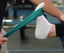 Athlete using four-way band stretching to strengthen her ankle after an injury - PNF exercises