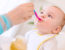 Mother feeding baby solid foods - Feeding babies peanut products reduces allergy risk
