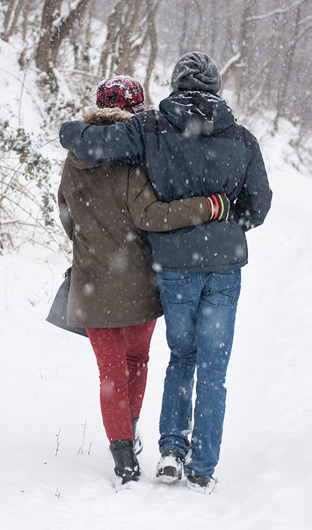Two people walking in snow - Cancer and cold weather
