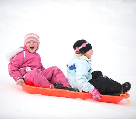 two kids sledding - sunburn and snow