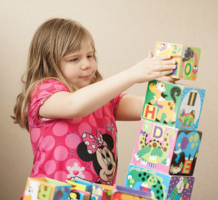 Young girl with BBS playing with stacking blocks - Rare diseases - Bardet Biedl Syndrome