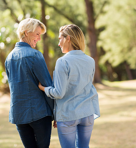 Mother and daughter chatting while walking arm in arm - Multiple Scelrosis