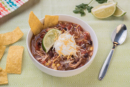 A bowl of tortilla soup topped with sour cream, a lime wedge and tortilla strips - What to look for in canned food