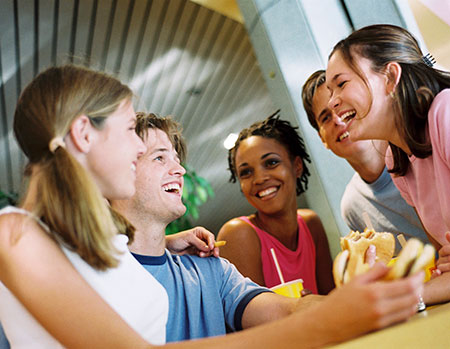 Group of teenagers eating lunch noting girls develop faster