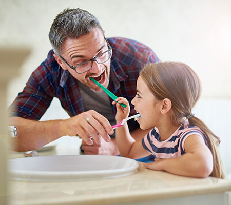 Father and daughter brush teeth. Dentist visits check mouth, gums and tongue for signs of oral cancer