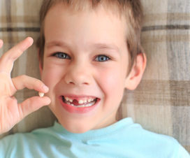 Young boy holding missing tooth