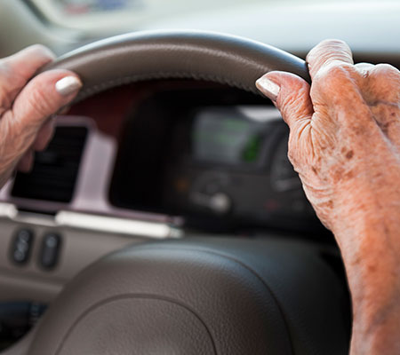 Elderly hands on a steering wheel