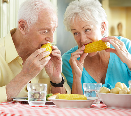 Elderly man and woman eating corn