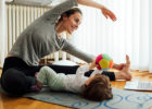 Mom stretching by toddler on floor - Body back after pregnancy