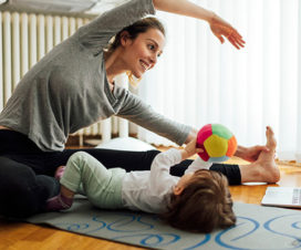 Mom stretching by toddler on floor - Body back after pregnancy
