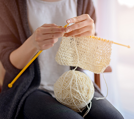Woman knitting with white yarn - Benefits of knitting