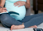 Pregnant woman sitting crossed legged writing in a notebook - Cancer treatment during pregnancy