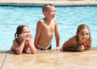 Three kids in a swimming pool posing for the camera - Dry drowning