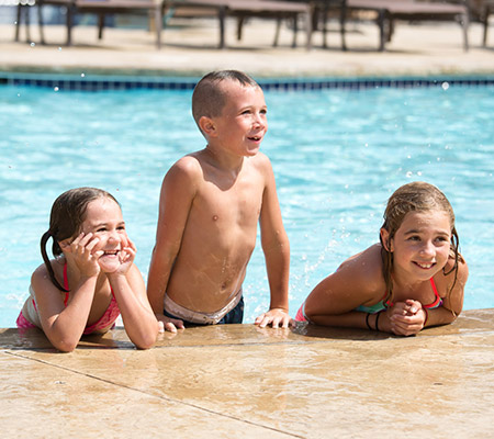 three kids in a swimming pool posing for the camera / dry drowning