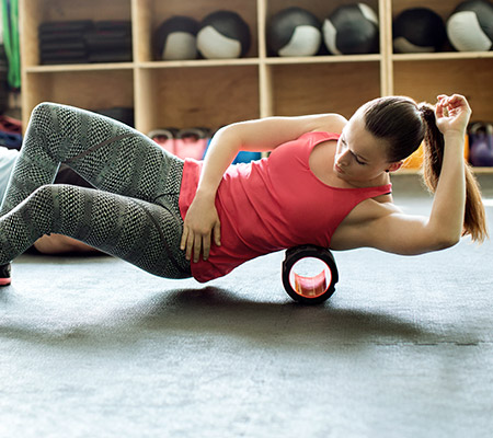 woman using a foam roller to work out the sides of her body / foam roller therapy