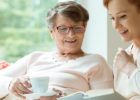 Senior woman and young woman enjoying a cup of tea and reading a book - What is palliative care?