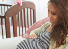 Pregnant woman sitting in a chair feeling her tummy and smiling - Third trimester expectations