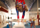 Girl balancing on a high beam on her hands - Gymnastics injuries