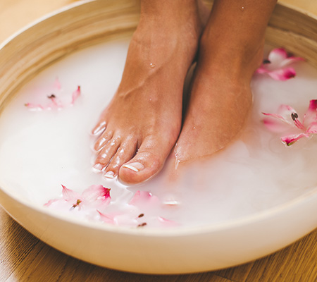 Woman soaking feet in a milk foot bath - Toenail fungus