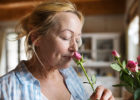 Senior woman smelling pink flowers - Sense of smell