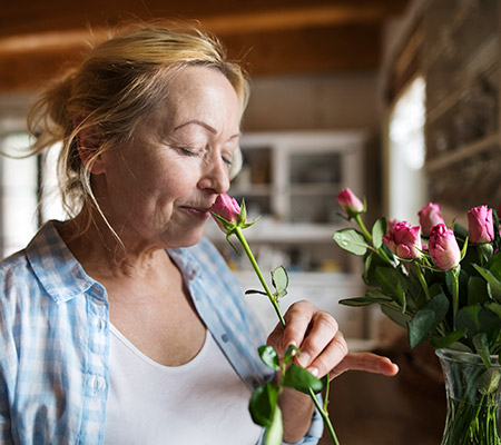 Senior woman smelling pink flowers - Sense of smell