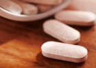 Multi-vitamin pills spilling out of bottle onto table - Can too many vitamins cause lung cancer?