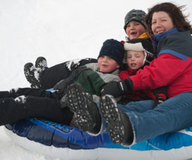 Family sliding down a hill in an inner tube - Tips for dealing with asthma in winter