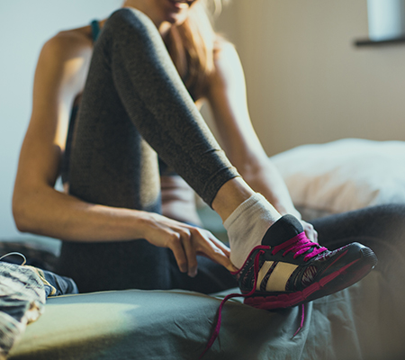 Woman putting on running shoes on the bed - Hammertoes