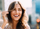 Young, beautiful woman smiling, brushing back hair - Gum disease and dental health linked to heart health