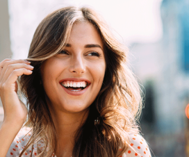 Young, beautiful woman smiling, brushing back hair - Gum disease and dental health linked to heart health