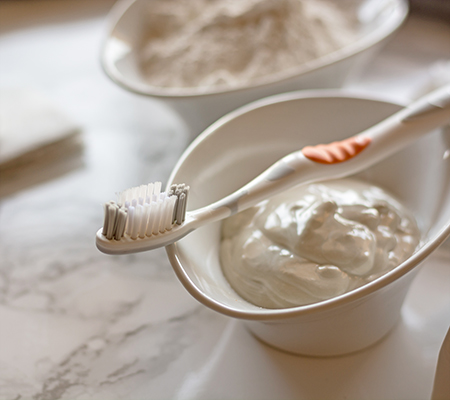 Bowl of homemade toothpaste and a toothbrush - Dental trend: Homemade toothpaste