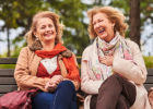 Two middle-aged women laughing on a park bench - Stress and your heart health