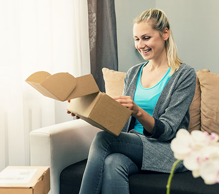 Woman opening a package on the couch - At-home genetic testing