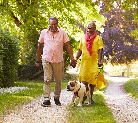 Couple walking their dog to get the benefits of sunlight and reduce seasonal affective disorder