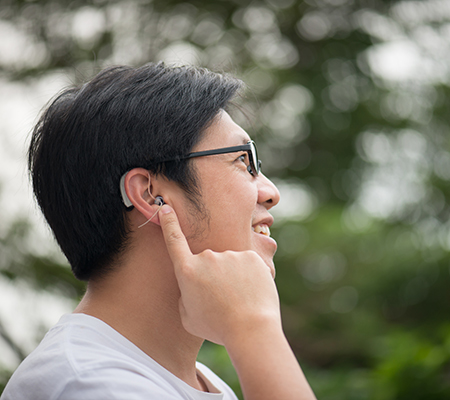 Man pointing to his hearing aid - When to see an audiologist