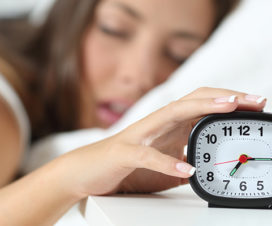 Girl in bed trying to turn off her alarm - Healthy morning routines