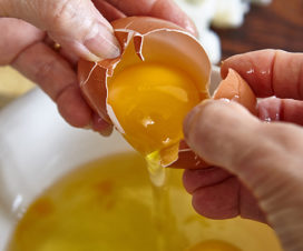 Woman cracking an egg into a bowl - Raw eggs