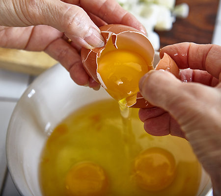 person cracking an egg into a bowl to consume raw egg for muscle gain