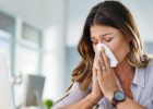 Woman blowing her nose at work - Superbugs, or antibiotic-resistant bacteria