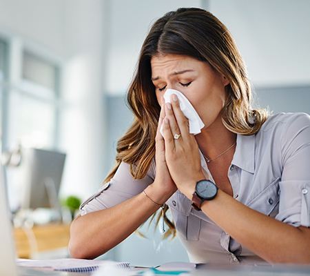 Woman blowing her nose at work - Superbugs, or antibiotic-resistant bacteria