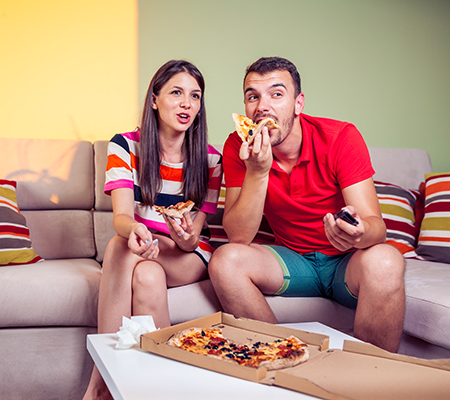 Couple eating on the couch - Mindless eating: Is eating in front of the TV bad for you?