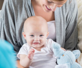 Baby sitting in mother's lap laughing - Lactation consultants