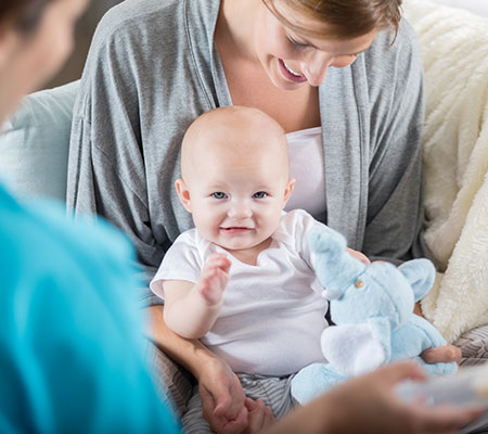 Baby sitting in mother's lap laughing - Lactation consultants