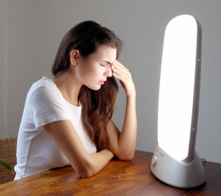 Woman sitting in front of a light - Light therapy for seasonal affective disorder