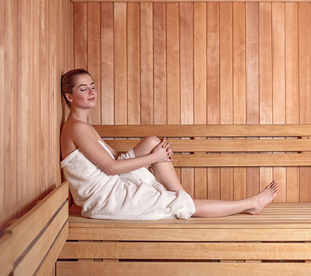 Girl in a sauna - Heart benefits of saunas